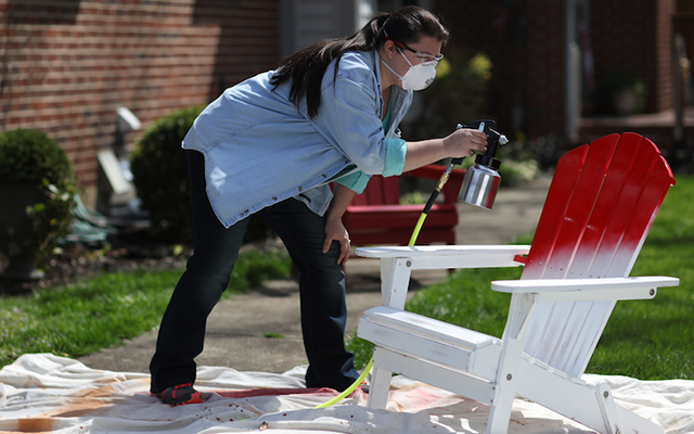 woman spray painting a yard chair