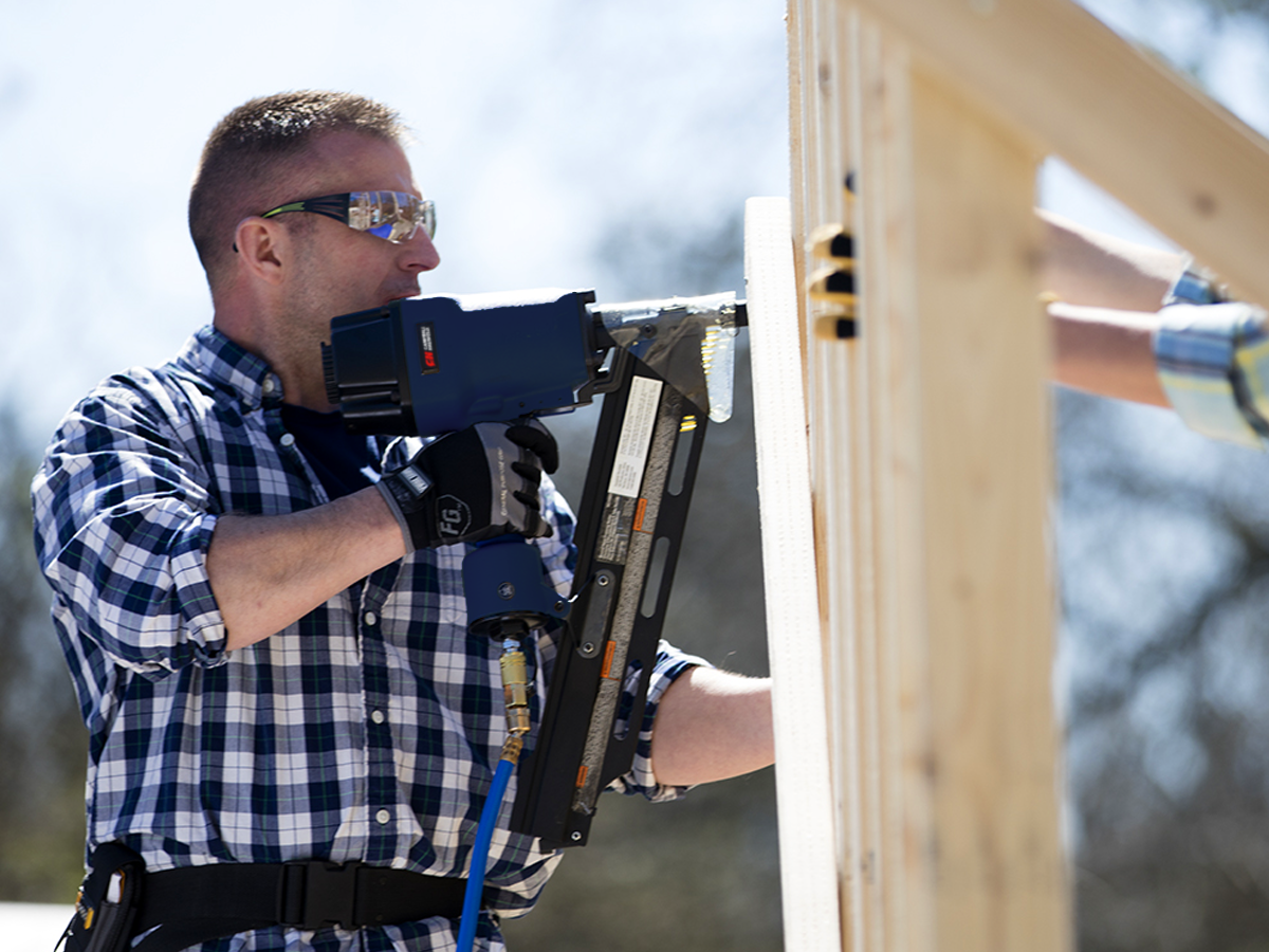 Carpenter using a nail gun to put nails into a new wall Stock Photo - Alamy